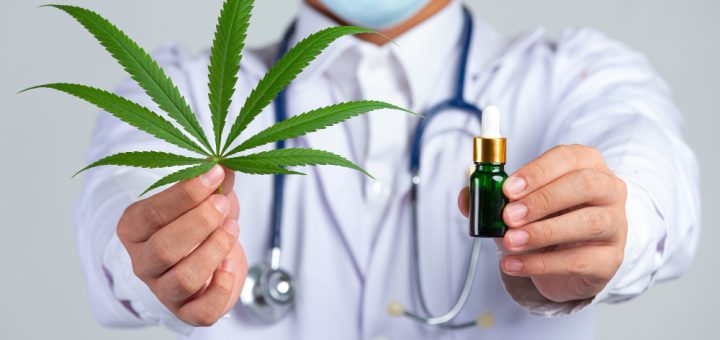 El uso medicinal del cannabis avanza con nuevas opciones terapéuticas - Healthcare professional holding a cannabis leaf and a CBD oil dropper, illustrating medical cannabis treatment in a clinical setting