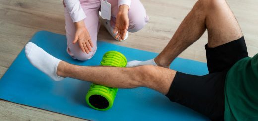 Therapist guiding leg foam rolling during a physical therapy session on a blue mat.