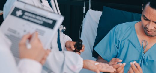 Doctor in white coat with clipboard and bottle explains medication to a male patient in a hospital bed, who holds pills in his hand.