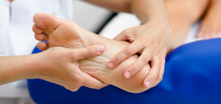 Physical therapist holding and kneading a patient's ankle during a massage.