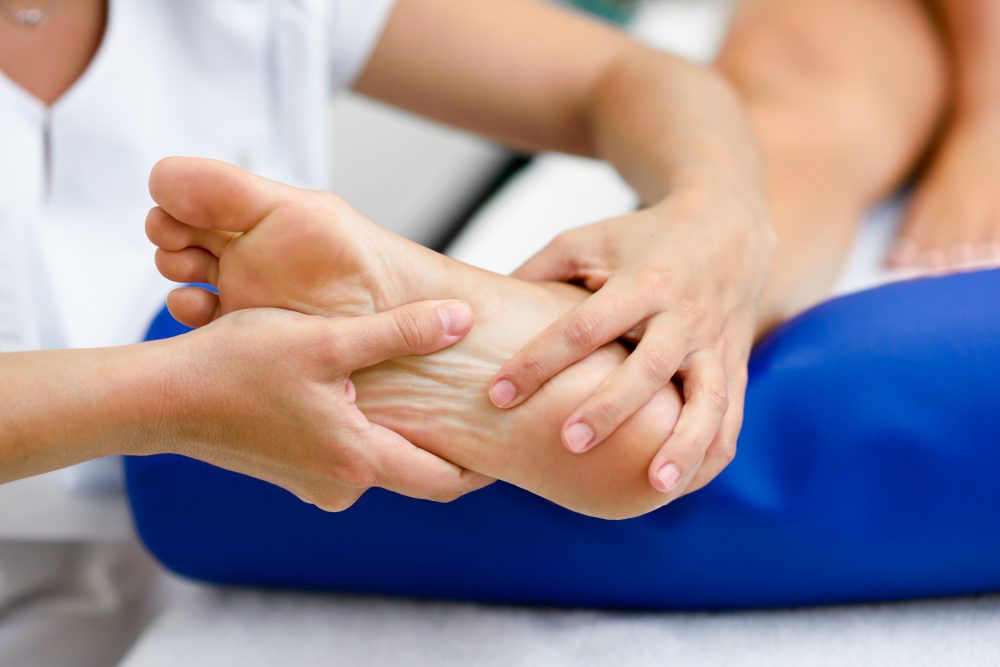 Physical therapist holding and kneading a patient's ankle during a massage.